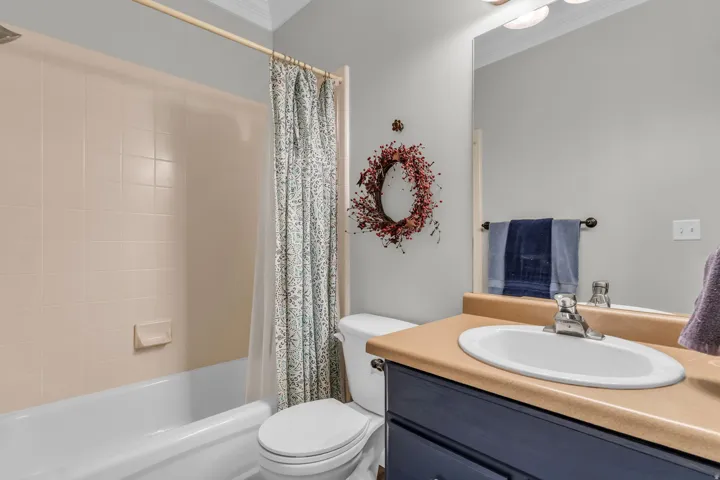Main Level Bath- Tub-shower combination with tiled surround, white vanity sink with chrome faucet, vanity mirror, and built-in vanity cabinetry