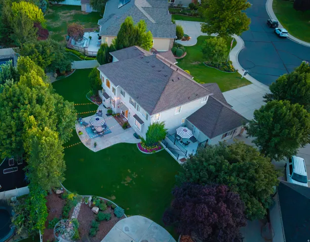 Expansive landscaped yard with a concrete patio, mature trees, and a decorative garden area