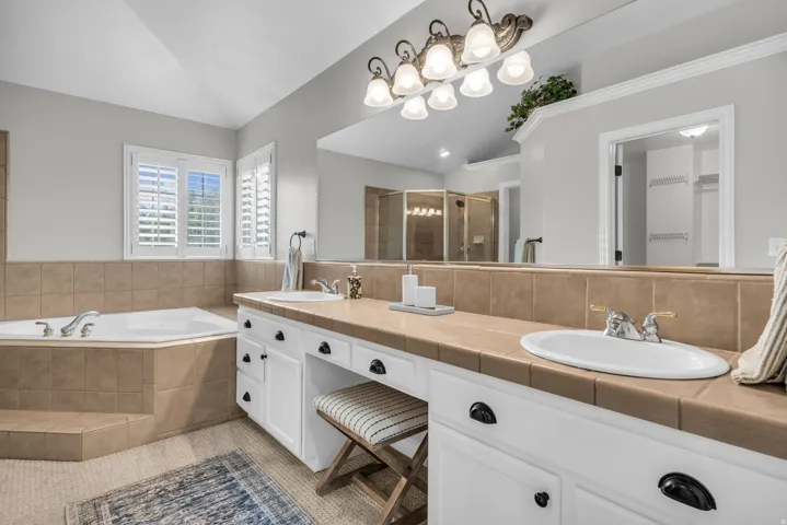 Master Bathroom (Upstairs)- Spa-inspired primary bathroom featuring dual vanities with white cabinetry and wood-finish countertops, polished nickel hardware, and vessel sinks