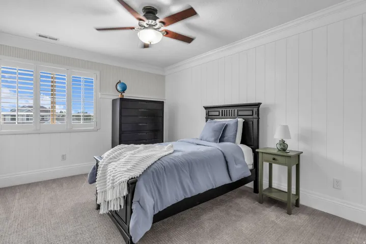 Upstairs Bright secondary bedroom featuring white shiplap walls, carpeted flooring, a ceiling fan with integrated lighting, plantation shutters