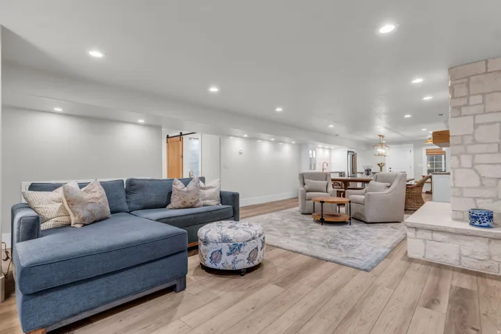 Basement- Recessed lighting, wood-finish flooring, stone-clad fireplace, light-toned walls, and a sliding barn door