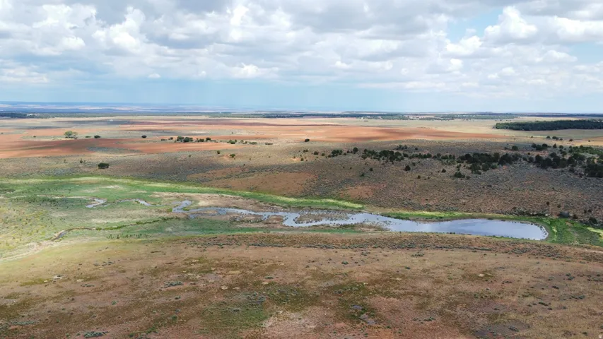 Expansive open terrain featuring natural water elements and distant treelines