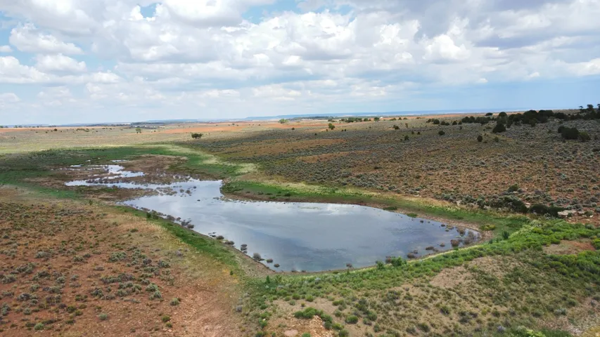 Expansive landscape featuring a natural water body, surrounding vegetation, and distant terrain