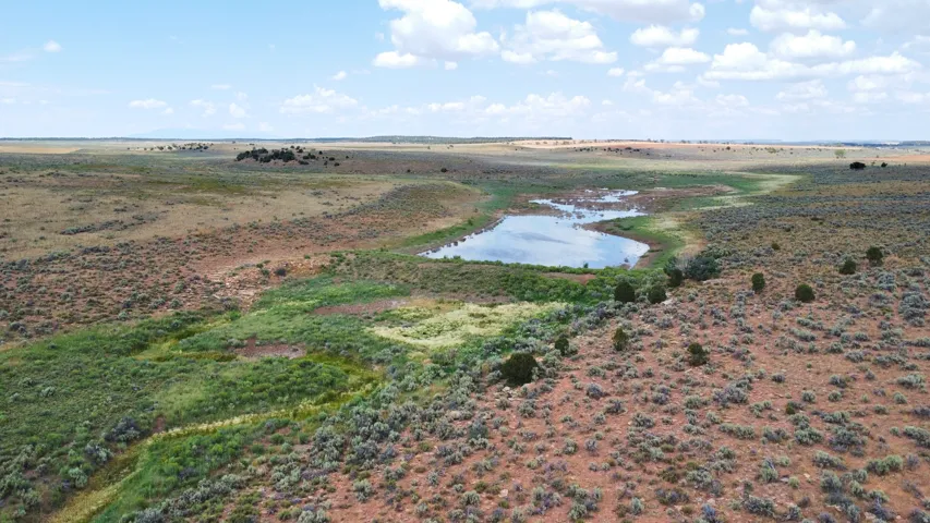 Expansive open landscape featuring a natural water body and varied terrain with sparse vegetation