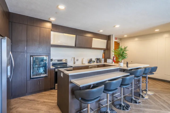 Kitchen featuring dark wood-finish cabinetry, stainless steel appliances, a beverage cooler, light countertops, and chevron-patterned wood-finish flooring