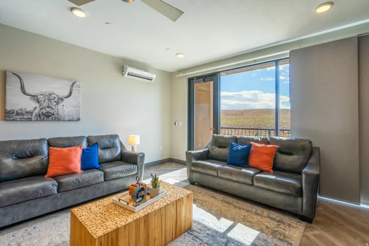 Sophisticated living room featuring floor-to-ceiling windows with panoramic landscape vistas, hardwood flooring, and dual leather seating arrangements