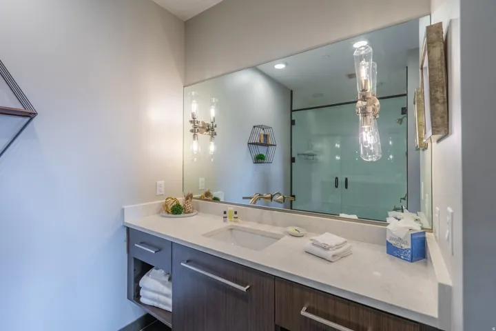 Single vanity with a light-toned countertop, undermount sink, and dark wood-finish cabinetry