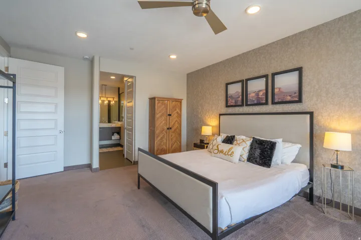 Recessed ceiling lighting, ceiling fan, textured accent wall, paneled interior doors, and an en-suite bathroom with dual vanity