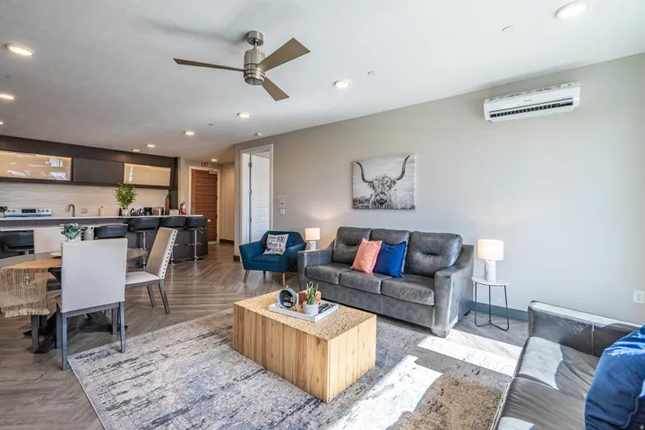 Open-concept living space featuring a gray upholstered sofa, wood-finish flooring throughout, and recessed ceiling lighting