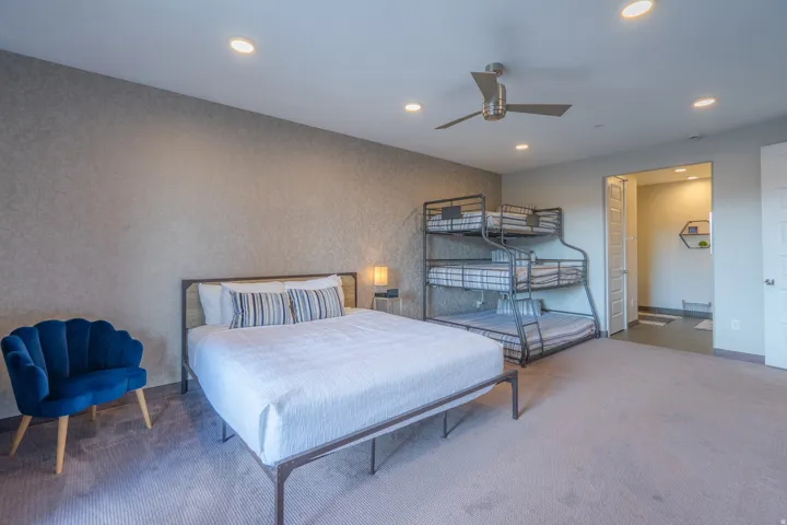 Recessed lighting throughout, modern ceiling fan, textured accent wall, and wood-finish door
