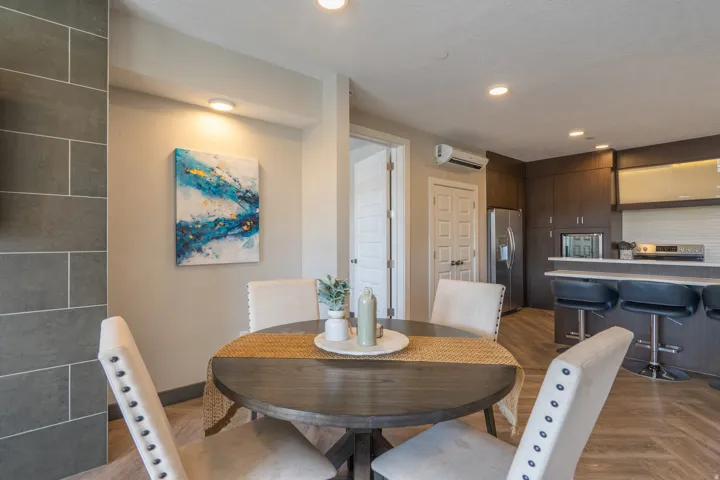 Modern dining area featuring a round wood-finish table with pedestal base, paired with upholstered dining chairs