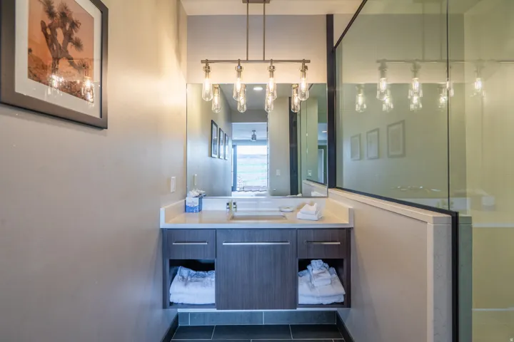Spa-inspired primary bathroom featuring a dual-sink vanity with wood-finish cabinetry, quartz countertop, and brushed nickel fixtures