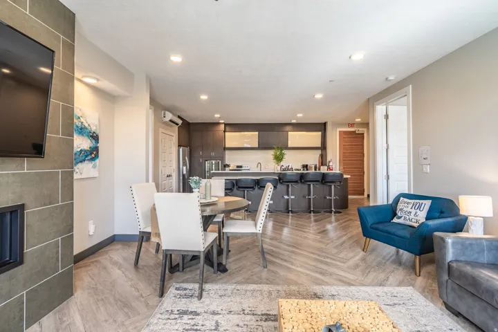 Open-concept living space featuring wood-finish flooring throughout, recessed ceiling lighting, and a modern kitchen with dark cabinetry, stainless steel appliances, and light-toned upper cabinets