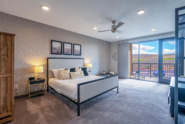 Spacious primary bedroom with floor-to-ceiling glass doors opening to a private balcony overlooking expansive landscape vistas