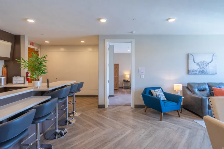 Kitchen island with seating for four, wood-finish flooring in a herringbone pattern, recessed lighting, and light-toned walls