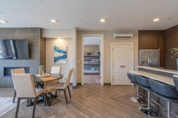 Open-concept living space featuring wood-finish flooring, recessed ceiling lighting, and a curved bar with stainless steel appliances