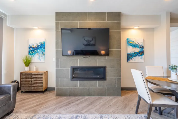 Fireplace with a tile surround, built-in entertainment niche, recessed lighting, and wood-finish flooring