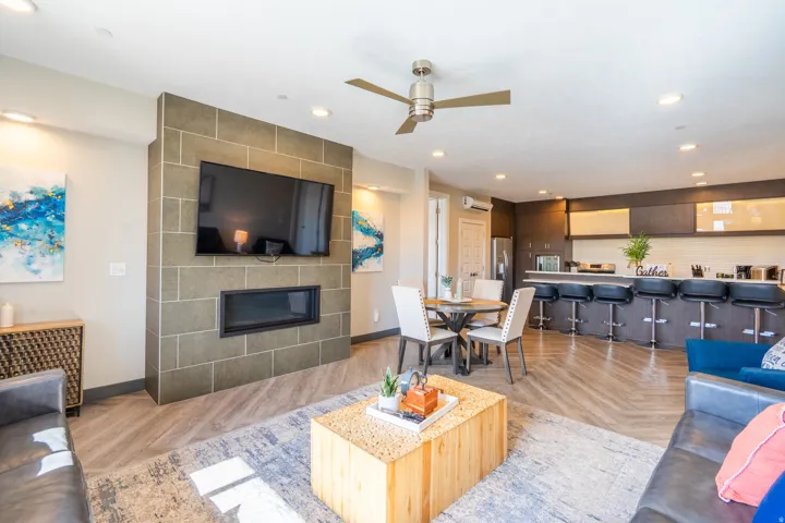 Open-concept living area featuring a tile-surround fireplace with integrated flat-screen television, wood-finish flooring throughout, and recessed ceiling lighting
