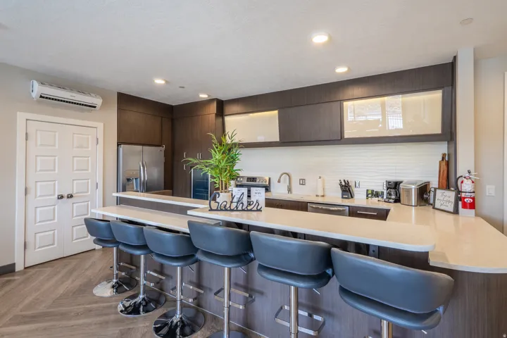 Kitchen featuring wood-finish flooring, dark wood-finish cabinetry, stainless steel appliances, and light-toned countertops