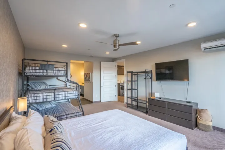 Recessed lighting, ceiling fan, wall-mounted television, and a split-system air conditioning unit