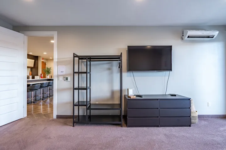 Recessed ceiling lighting, wall-mounted climate control unit, and a six-drawer dresser