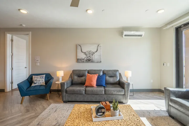 Bright, open living space featuring a wood-finish floor, recessed ceiling lighting, and a wall-mounted air conditioning unit