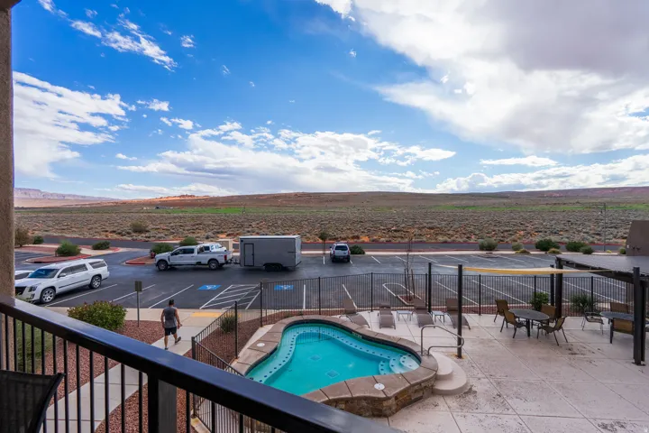 Outdoor pool and spa with stone coping, surrounded by a paved patio area