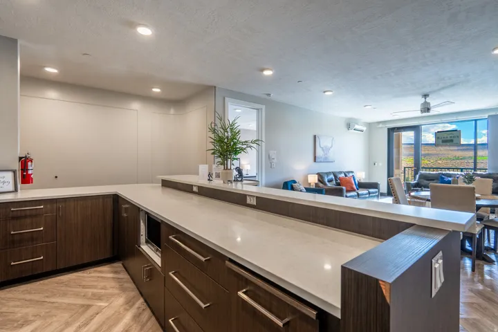 Quartz countertops, wood-finish flooring, recessed lighting, and dark wood-finish cabinetry