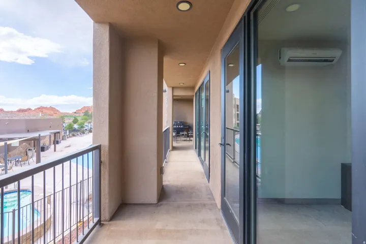 Covered balcony with recessed lighting, metal railings, and multiple glass panel doors