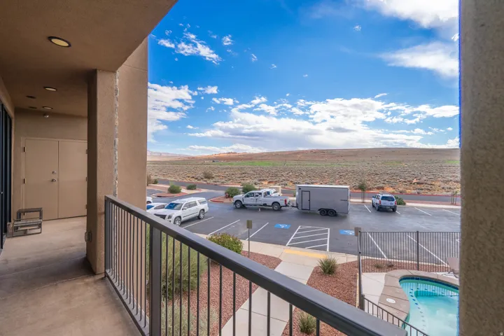 Private balcony with metal railing, recessed lighting, and expansive desert landscape