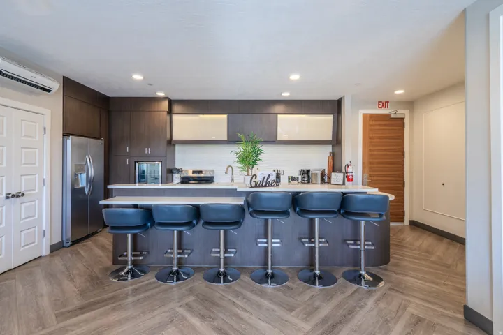 Herringbone wood-finish flooring, dark wood-finish cabinetry, white countertop, stainless steel appliances, and recessed lighting