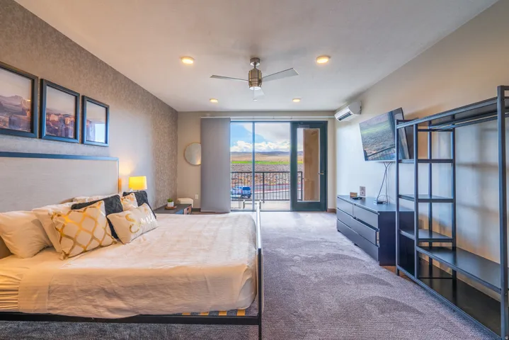 Recessed lighting, ceiling fan, direct access to a balcony, wall-mounted air conditioning unit, and textured accent wall