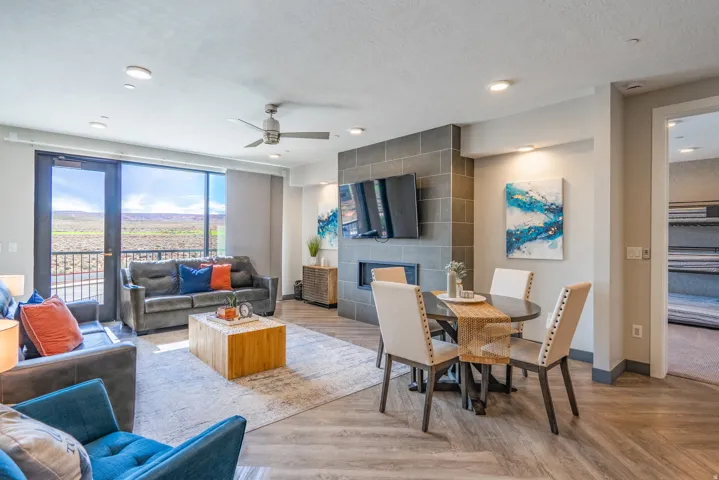 Open-concept living area featuring wood-finish flooring, a gas fireplace with tile surround and mounted television, and expansive windows framing panoramic mountain vistas
