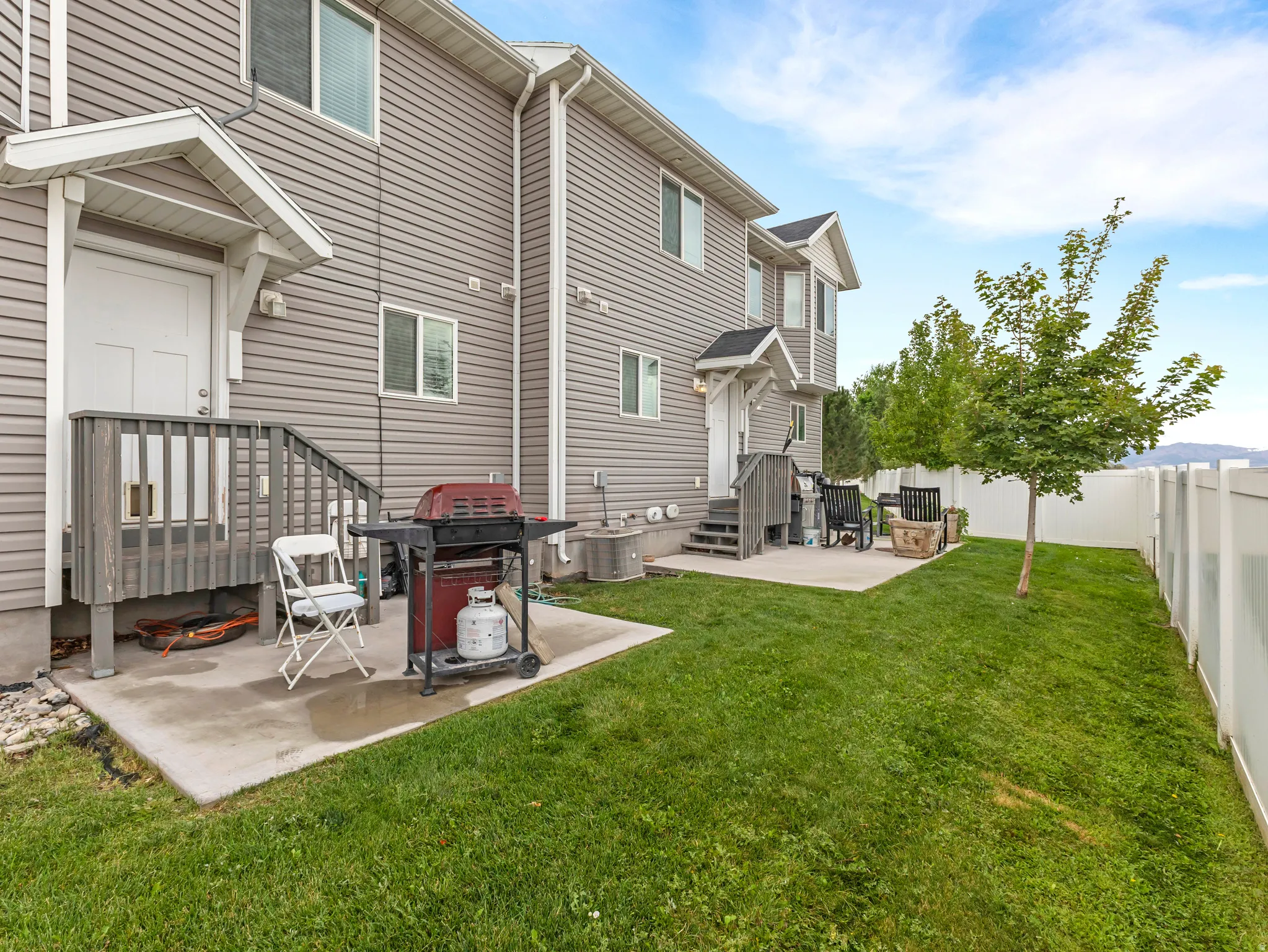 Spacious backyard oasis featuring a manicured lawn, mature landscaping, and a concrete patio with grill station