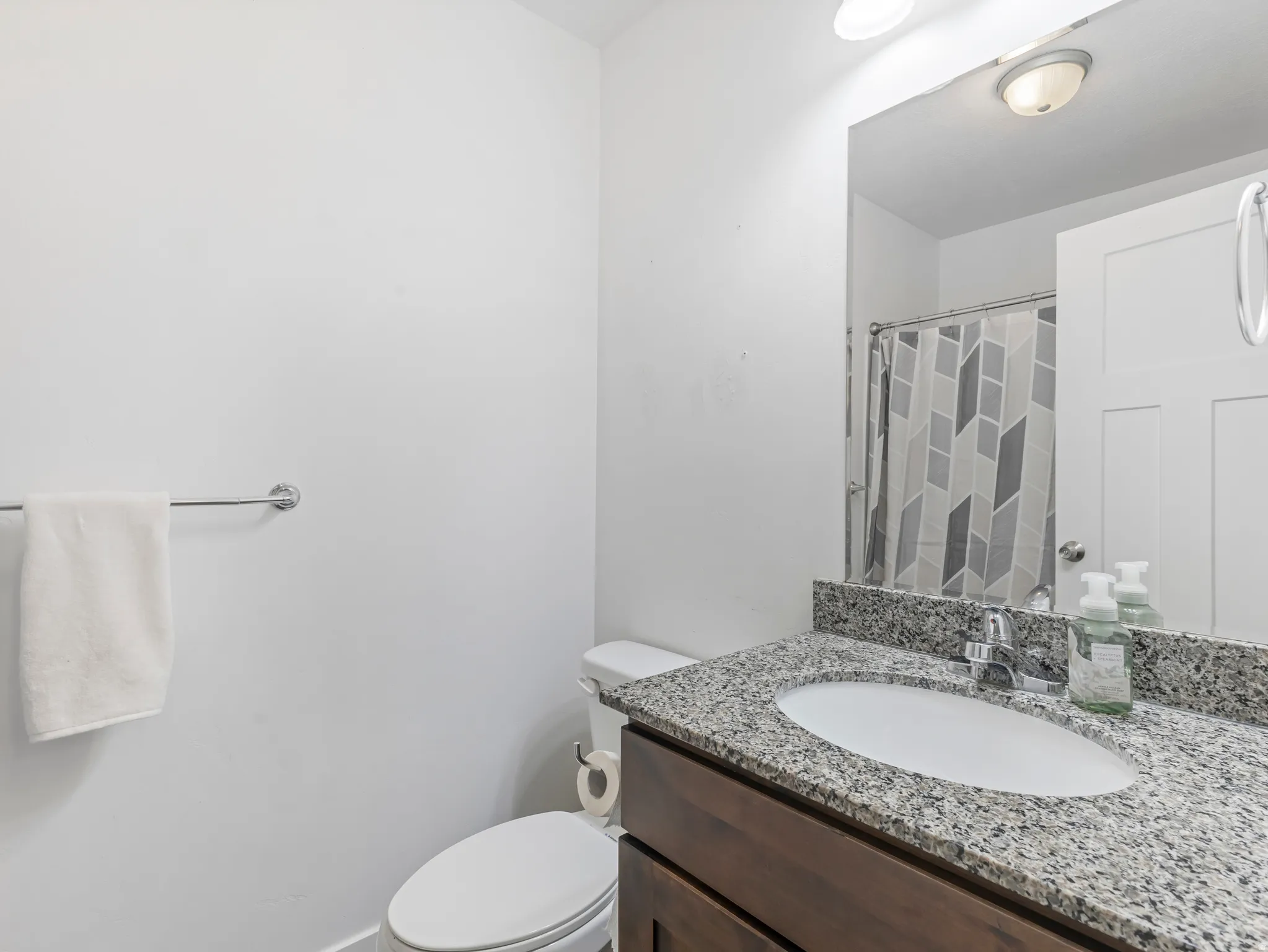 Modern bathroom featuring a granite-topped vanity with an undermount sink, bronze-finish cabinetry, and a large framed mirror