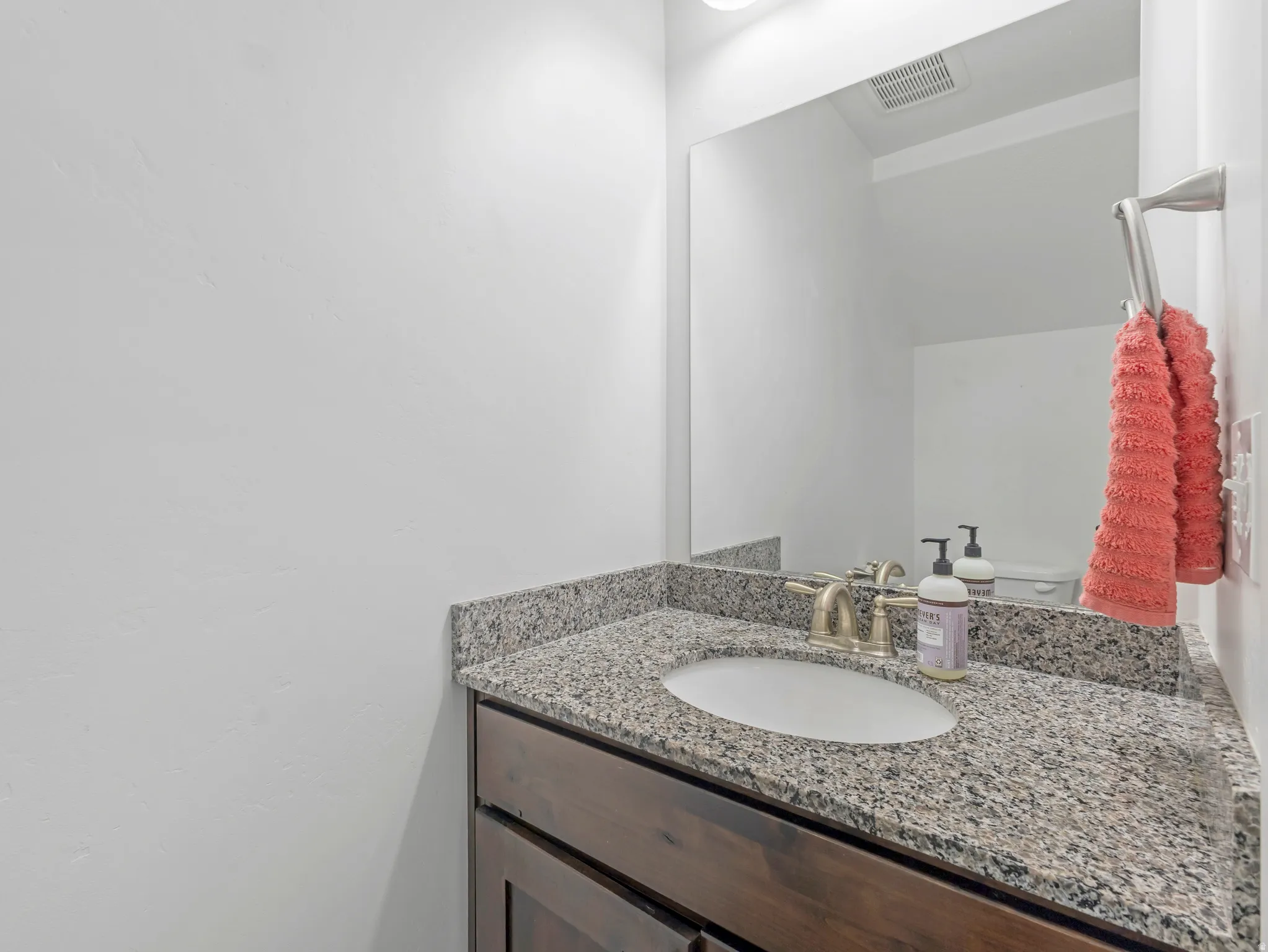 Modern bathroom vanity featuring a speckled quartz countertop, undermount circular sink, and polished chrome faucet