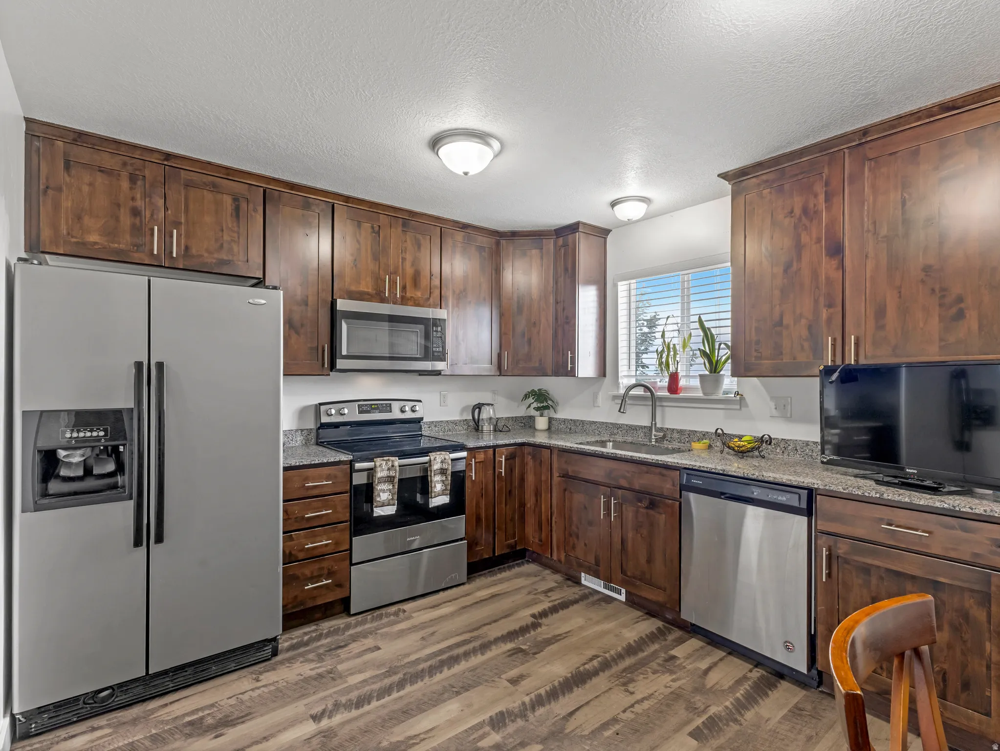 Kitchen featuring wood-finish flooring, dark wood cabinetry, and stainless steel appliances