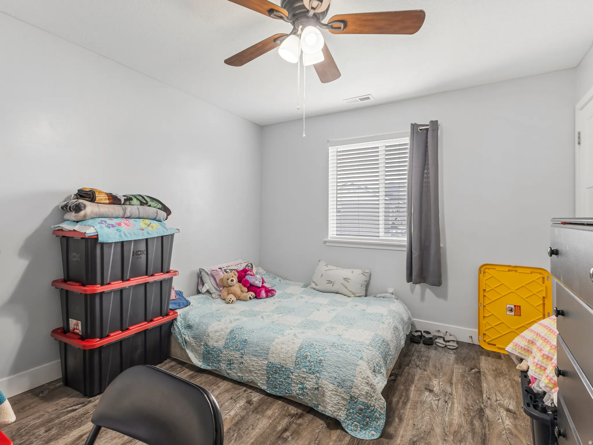 Wood-finish flooring, white walls, and a window with blinds and drapes