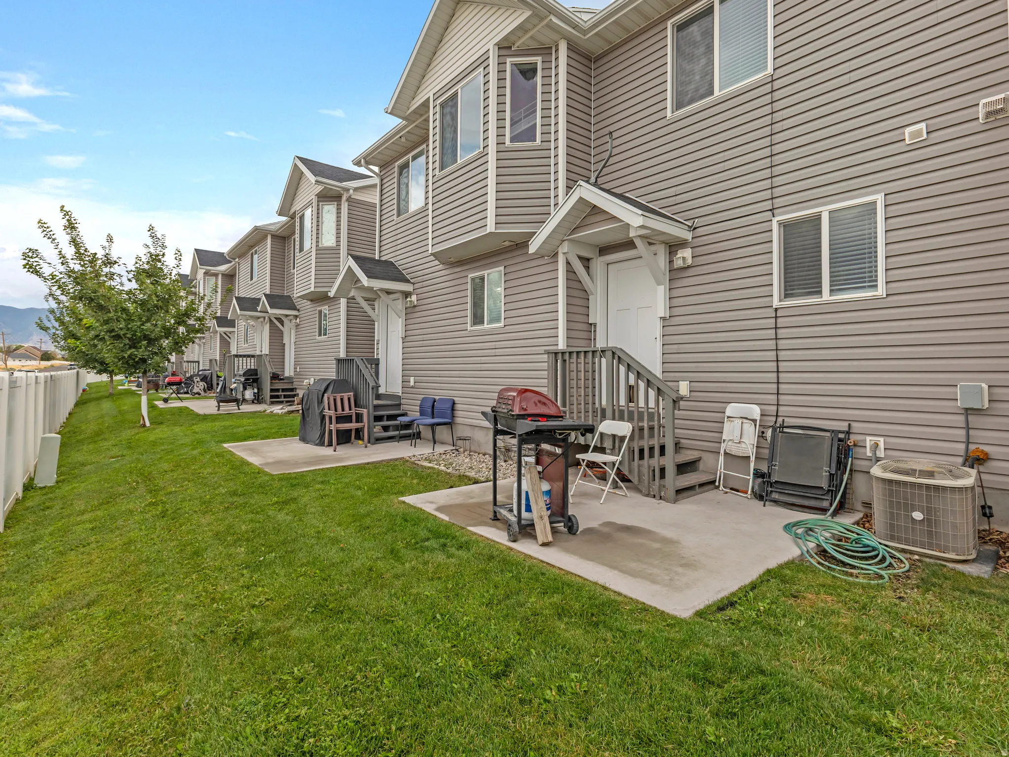 Spacious backyard oasis featuring a manicured lawn, concrete patio with outdoor seating areas, and mature landscaping