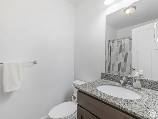 Modern bathroom featuring a granite-topped vanity with an undermount sink, bronze-finish cabinetry, and a large framed mirror