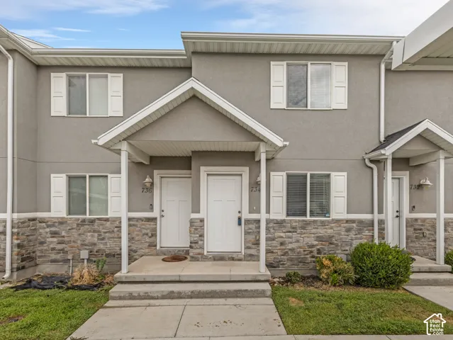 Stucco exterior with stone veneer accents, covered entry, and white window shutters