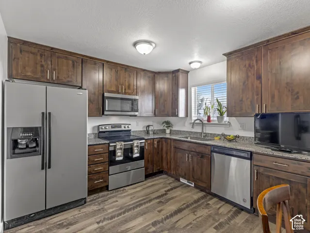 Kitchen featuring wood-finish flooring, dark wood cabinetry, and stainless steel appliances