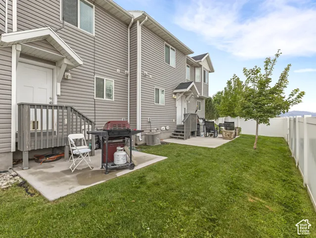 Spacious backyard oasis featuring a manicured lawn, mature landscaping, and a concrete patio with grill station