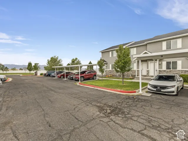 Spacious parking area with dedicated spaces and professional landscaping featuring mature trees, manicured lawn, and vibrant red accent borders