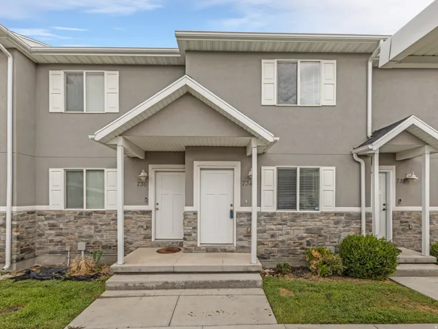 Stucco exterior with stone veneer accents, covered entry, and white window shutters