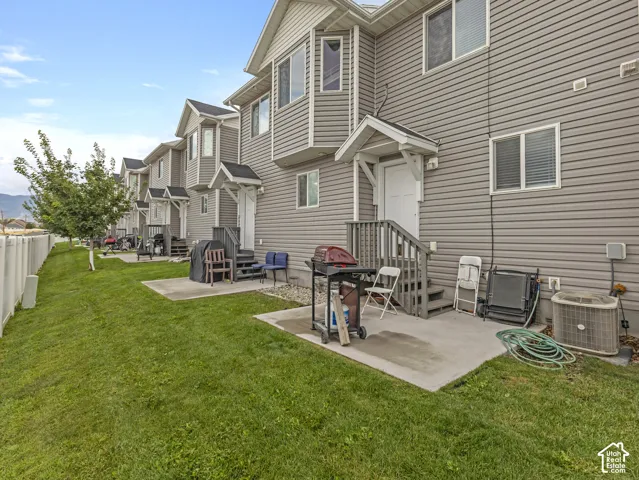 Spacious backyard oasis featuring a manicured lawn, concrete patio with outdoor seating areas, and mature landscaping