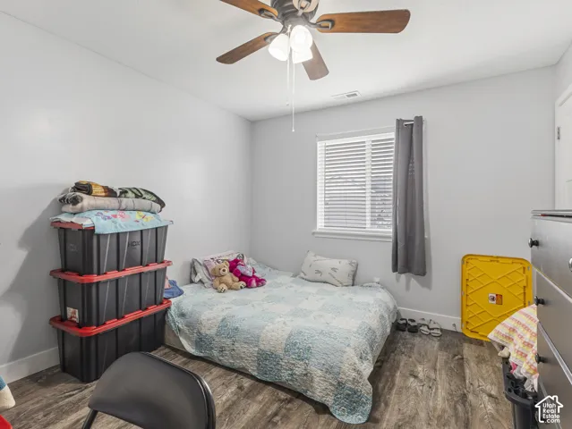 Wood-finish flooring, white walls, and a window with blinds and drapes