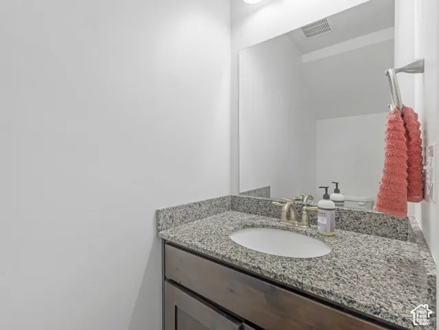 Modern bathroom vanity featuring a speckled quartz countertop, undermount circular sink, and polished chrome faucet