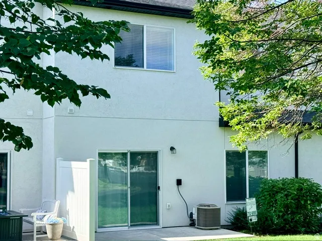 White stucco exterior with a black shingle roof