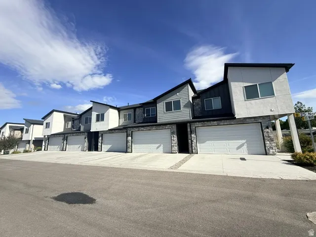 Modern townhome exteriors featuring multiple material finishes, attached garages with white panel doors, and concrete driveways